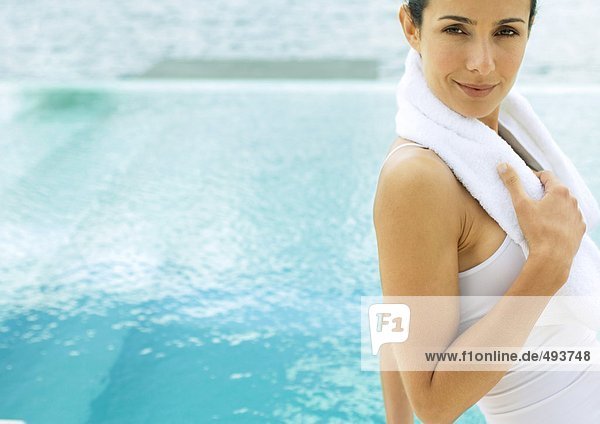 Frau mit Handtuch um den Hals  Pool im Hintergrund