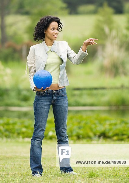 Woman holding ball and pointing out of frame
