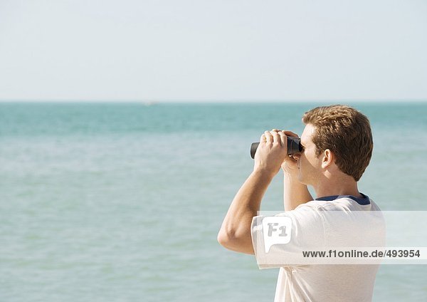 Man looking out to sea with binoculars