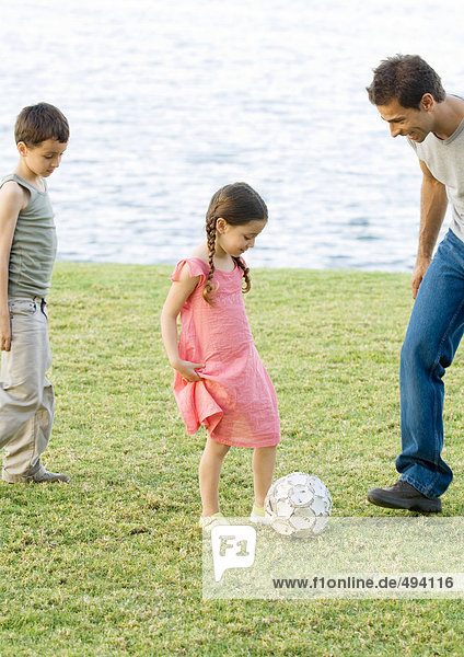 Vater spielt Fußball mit Kindern
