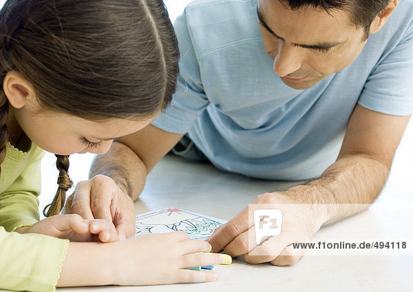 Man lying on floor drawing with daughter