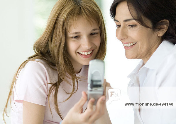 Girl and mature woman looking at cell phone together