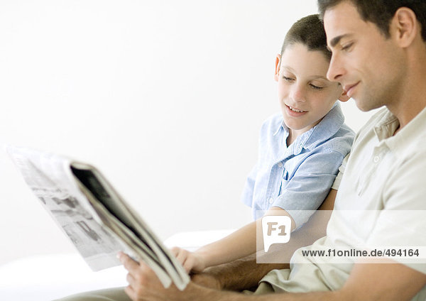 Mann und Sohn lesen gemeinsam Zeitung
