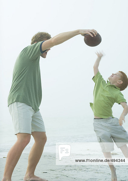 Mann beim Ballspielen mit Sohn am Strand