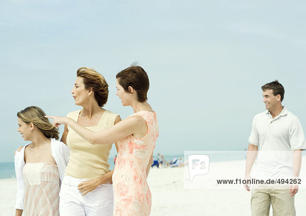 Frau mit Freundin und Teenagermädchen am Strand  zeigt auf Distanz