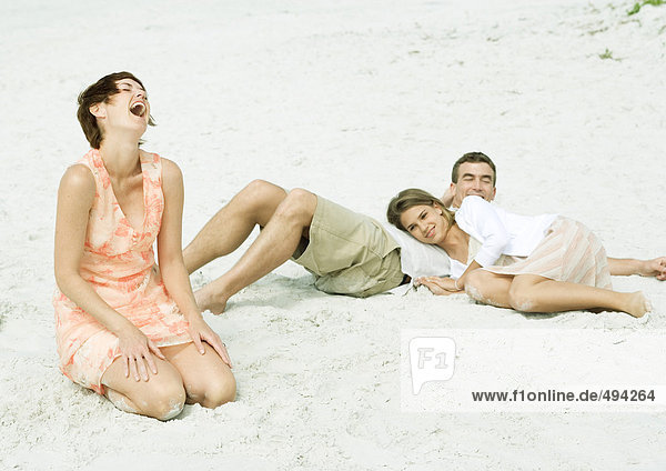 Familie am Strand  Teenager-Mädchen ruht Kopf auf dem Bauch des Vaters  während Mutter lacht