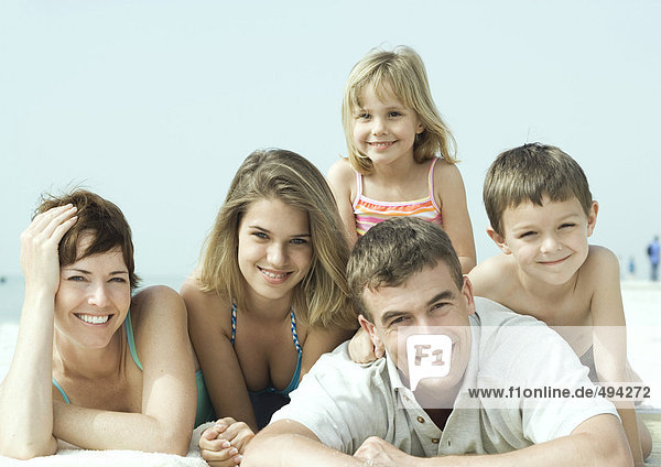 Family lying on beach  smiling  portrait