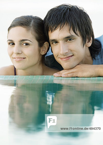 Young couple with heads by edge of water  close-up