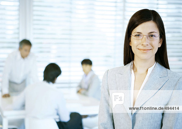 Geschäftsfrau lächelt vor der Kamera  Menschen arbeiten im Büro im Hintergrund