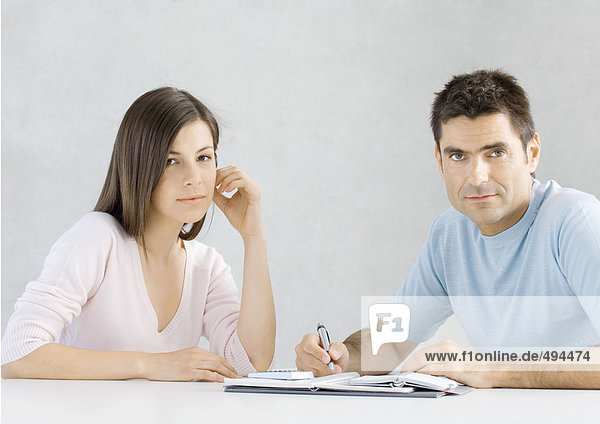 Couple working on budget  looking at camera