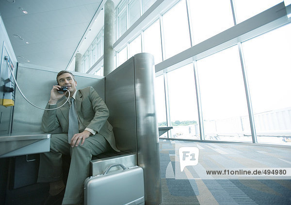 Businessman using pay phone in airport