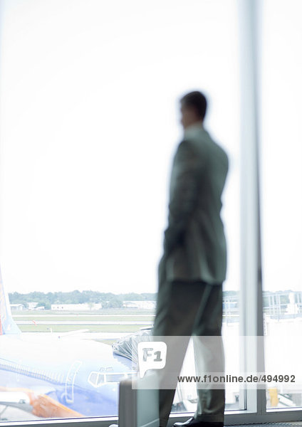 Mann steht am Fenster im Flughafen