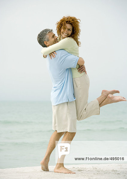 Man holding woman on beach