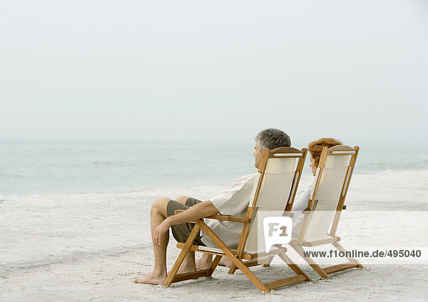 Couple sitting in beach chairs  looking at view