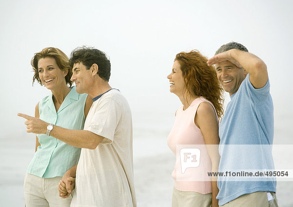 Two mature couples standing on beach