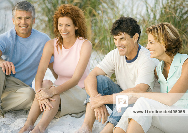 Two mature couples sitting on beach