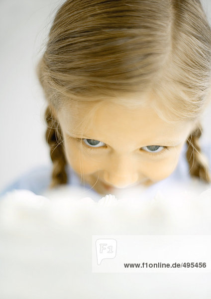 Girl lowering head to eat cake