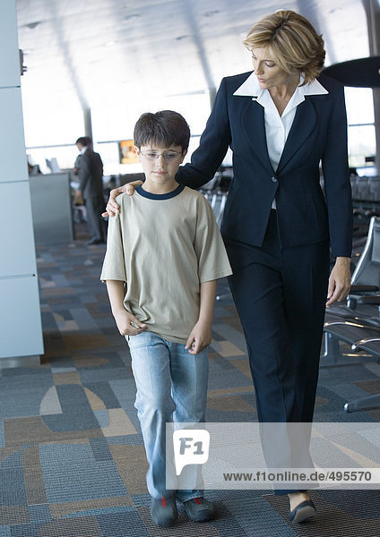 Airline attendant walking with boy in airport