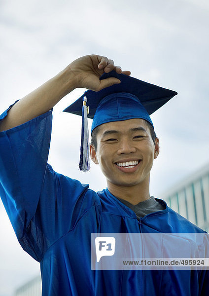 Male graduate with hand on cap