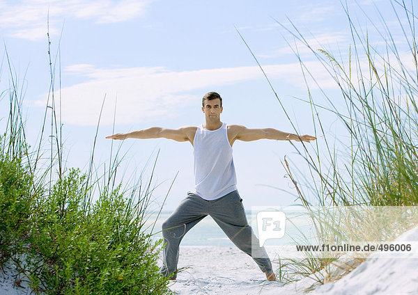 Mann beim Stretchen am Strand