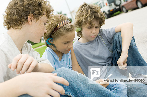 Kinder sitzen auf der Straße  eines mit mp3-Player