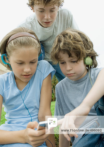 Kinder mit Kopfhörern und Blick auf den mp3-Player