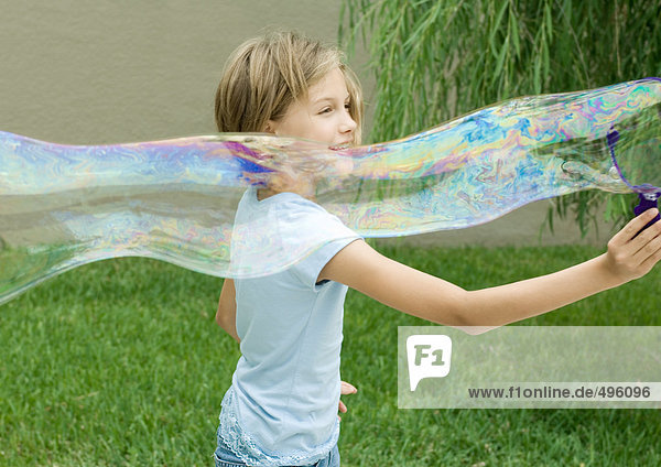 Mädchen macht lange Blase mit Blasenstab