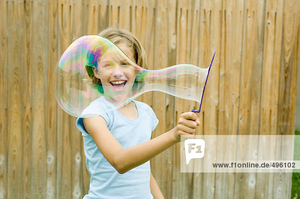 Mädchen macht Blase mit Blasenstab