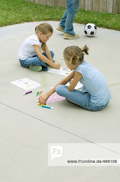 Mädchen sitzen auf der Einfahrt  malen und zeichnen