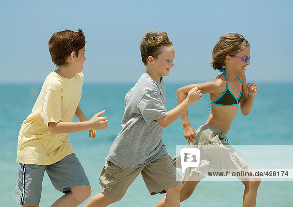 Drei Kinder beim Rennen am Strand