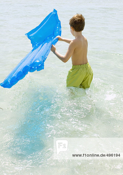 Junge mit Luftmatratze im Meer