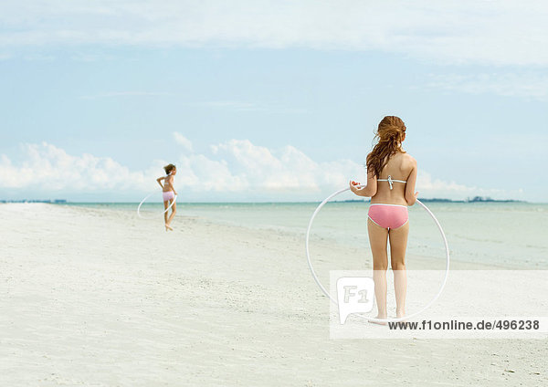 Mädchen spielen mit Plastikreifen am Strand