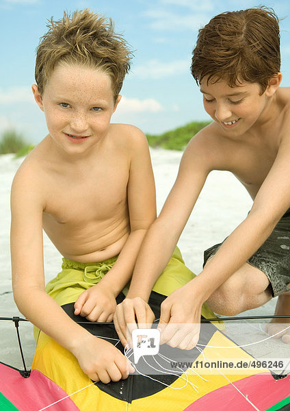 Zwei Jungen entwirren Drachenschnur am Strand