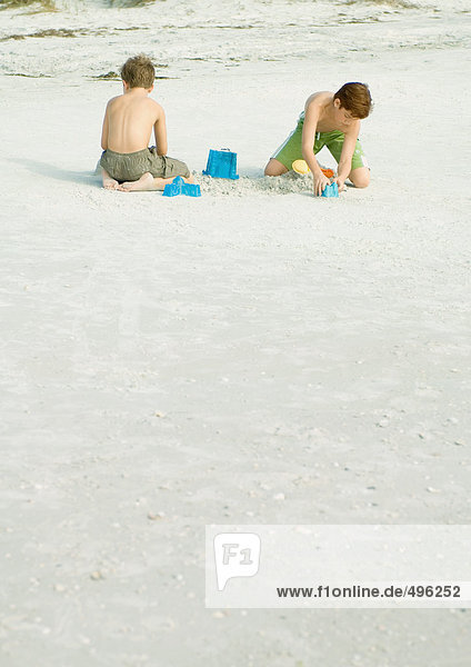 Jungen spielen im Sand am Strand