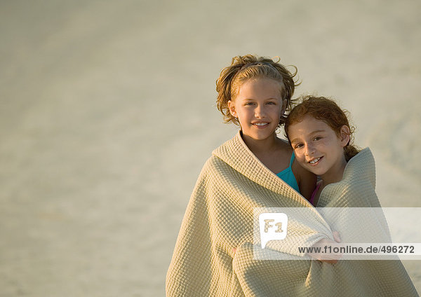 Zwei Mädchen in Handtuch gewickelt zusammen am Strand