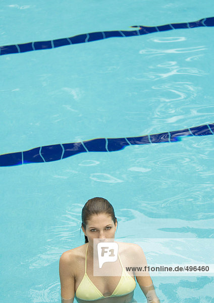Frau steht im Pool und schaut in die Kamera.