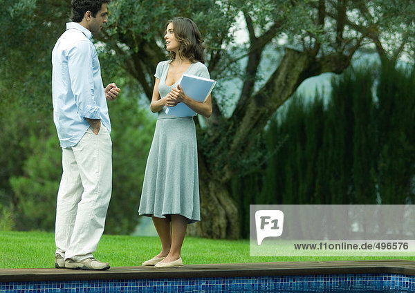 Mann und Frau reden neben dem Pool