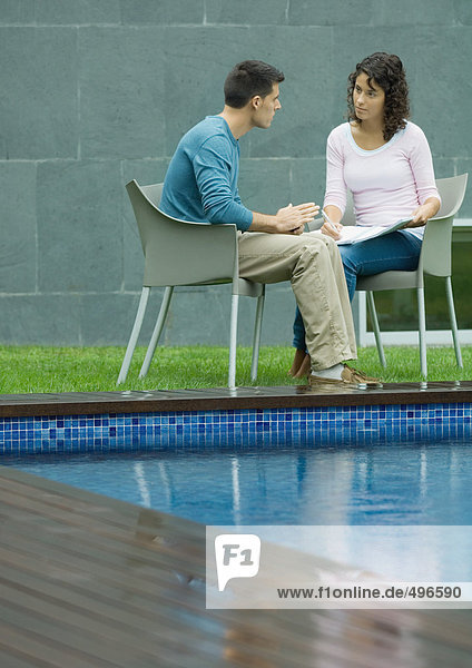 Mann und Frau im Gespräch am Pool