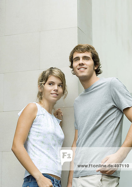 Junger Mann und Frau  die sich an die Wand lehnen  lächelnd