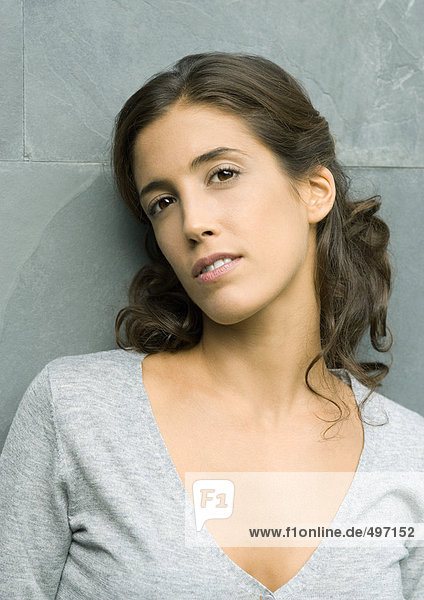 Woman leaning against wall  head and shoulders  portrait