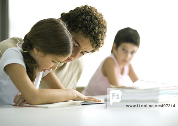 Teenage boy helping younger sister with homework