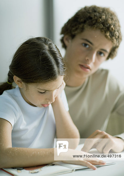 Teenage boy helping younger sister with homework