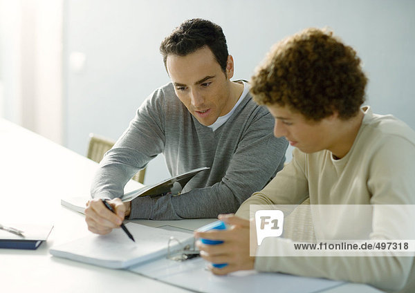 Mann hilft Teenager-Sohn bei den Hausaufgaben