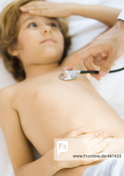 Arzt hält Stethoskop an die Brust des Jungen