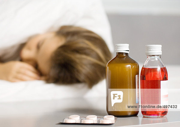 Mädchen im Bett liegend  Medikamente neben dem Bett im Vordergrund