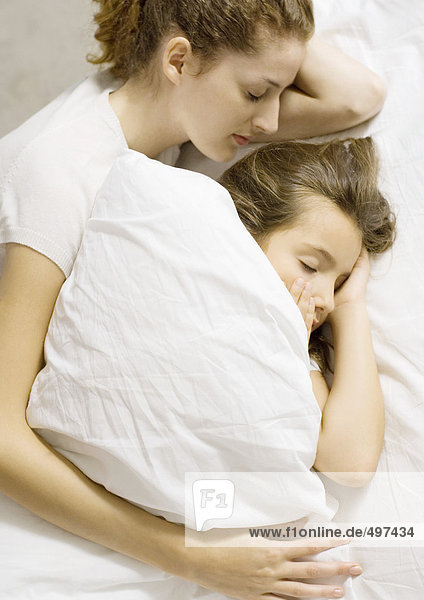 Mutter und Tochter schlafen zusammen im Bett.