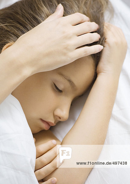 Mädchen schlafend im Bett  Mutter streichelt Kopf