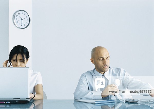 Office  man holding telephone while woman uses computer