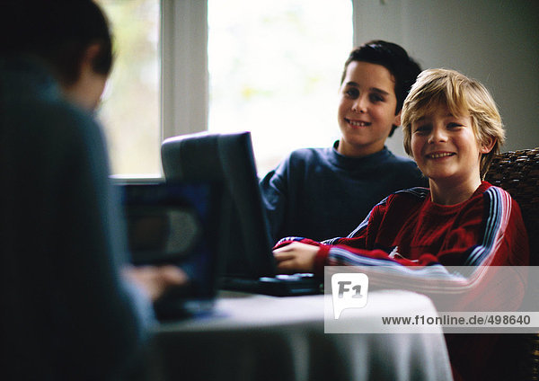 Two children using laptop and smiling