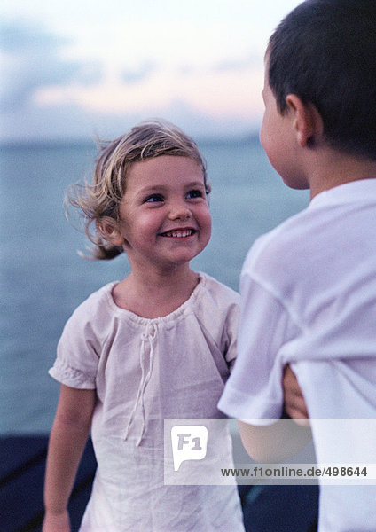 Girl smiling at boy near sea